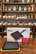 13.8cm cast-iron square griddle skillet with bamboo base for cooking and serving hot sizzling dishes.