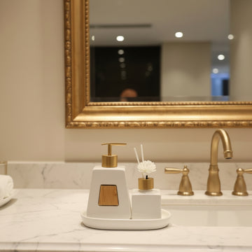 Luxury white and gold bathroom accessory set including soap dispenser, toothbrush holder, tumbler, reed diffuser, and tray for modern bathroom decor.