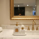 Luxury white and gold bathroom accessory set including soap dispenser, toothbrush holder, tumbler, reed diffuser, and tray for modern bathroom decor.