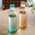 Reusable glass drinking bottle with time tracking scale for water, juice, iced coffee, smoothies, and cold beverages.